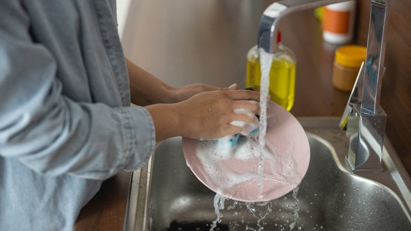 Pessoa lavando a louça - yacobchuk/iStock