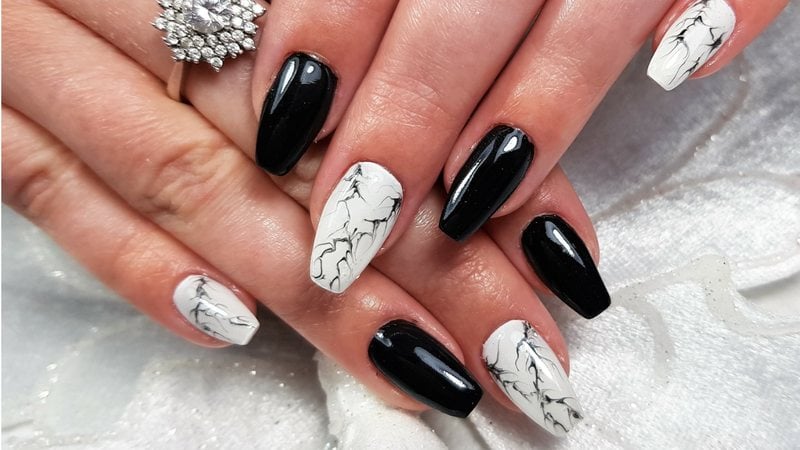 Formas diferentes de inovar a unha com esmalte preto e branco. - Wirestock / istock