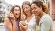 Amigas rindo enquanto olham para tela de celular