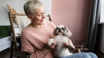 Mulher idosa com cachorro da raça Shih Tzu