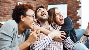 amigos se abraçando e se divertindo, sentados em sofá