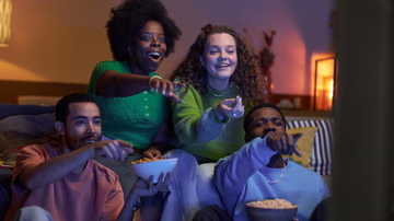 amigos sentados comendo pipoca, se divertindo e vendo filme