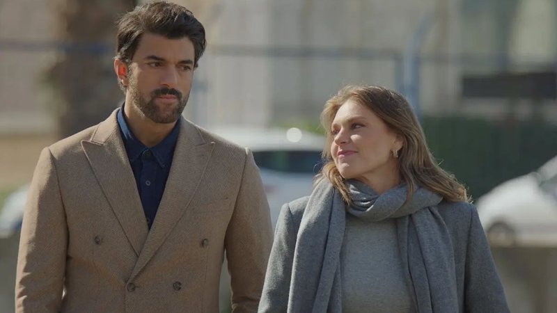casal protagonista de novela andando de mãos dadas em estacionamento