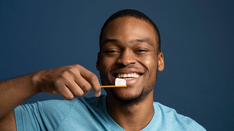 Homem sorridente escovando os dentes