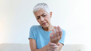 Mulher idosa com dor nas articulações da mão.