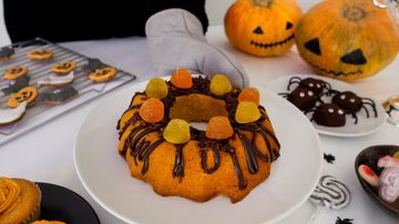 bolo de coloração laranja ao lado de abóboras de halloween