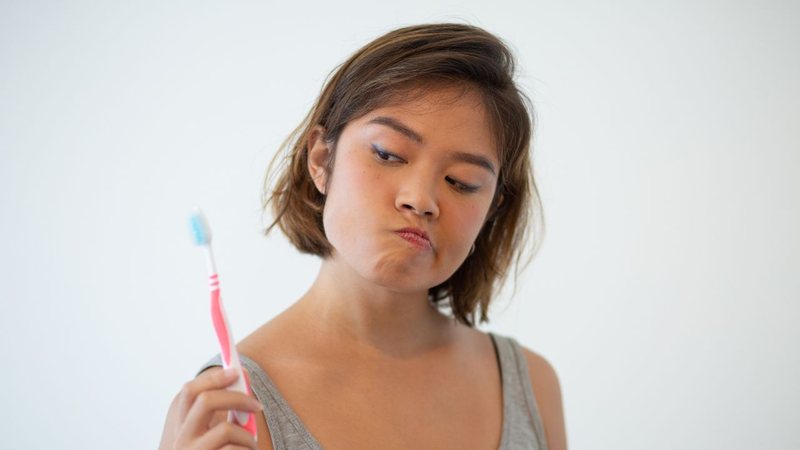 Mulher fazendo careta enquanto segura escova de dentes