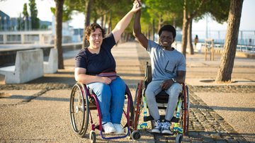 Homem e mulher, cada um em sua cadeira de rodas, na calçada