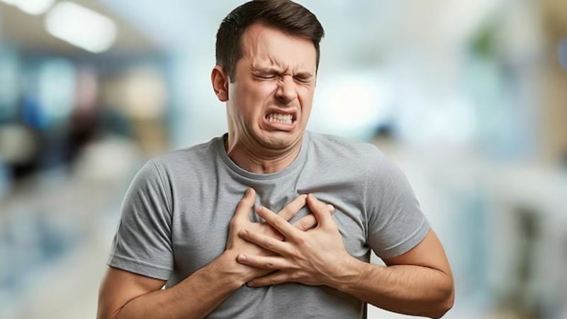 homem sofrendo com dor no peito, com as duas mãos sob o peito.