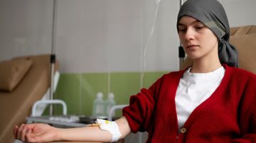 Jovem sentada fazendo quimioterapia