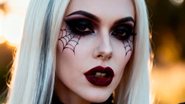mulher com maquiagem de teias de aranha e batom escuro
