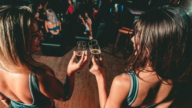 duas mulheres brindando com taças nas mãos em festa
