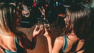 duas mulheres brindando com taças nas mãos em festa