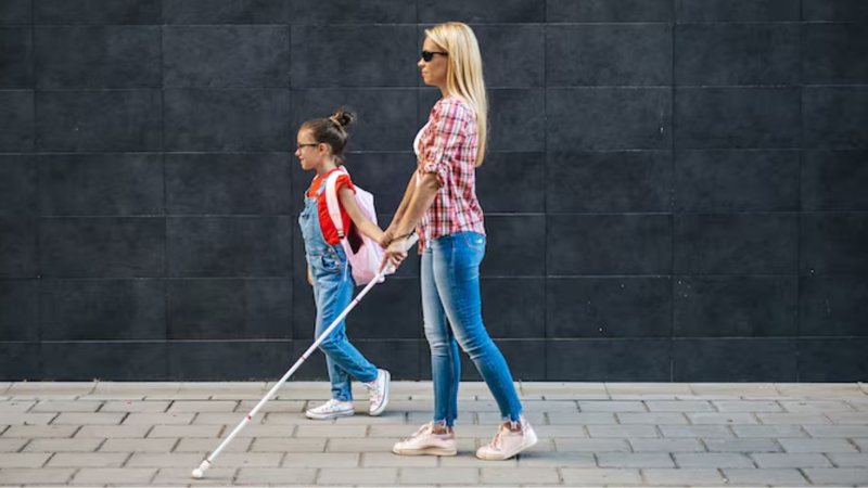 pessoa com deficiência visual caminhando ao lado de criança