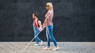 pessoa com deficiência visual caminhando ao lado de criança