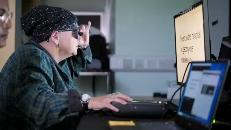 Idosa fazendo uso de nova tecnologia para a visão em frente à tela de computador