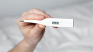 indivíduo segurando termômetro após medir a temperatura corporal