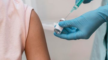 Pessoa aplicando vacina em paciente