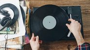 pessoa segurando disco de vinil prestes a coloca-lo em vitrola.
