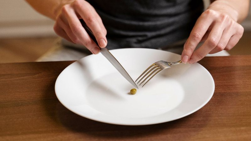 pessoa cortando uma ervilha no meio em uma dieta restritiva