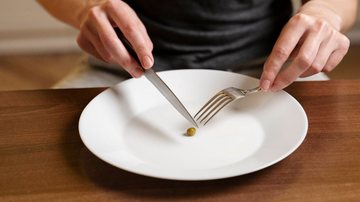 pessoa cortando uma ervilha no meio em uma dieta restritiva