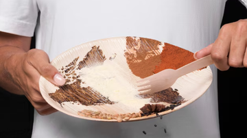 Homem segurando prato de comida com restos de alimentos