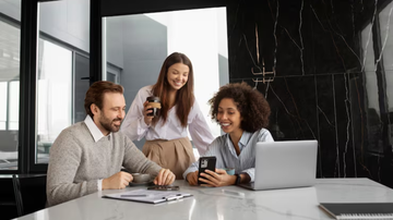 jovens adultos em escritório olhando o computador e conversando.