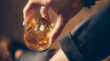 Indivíduo com copo de bebida na mão.