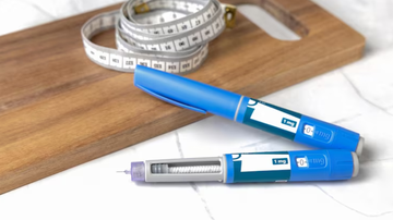 canetas emagrecedoras dispostas sob mesa ao lado de fita métrica.