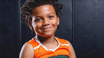 Kaden Stevenson aos 7 anos posando sob fundo escuro.