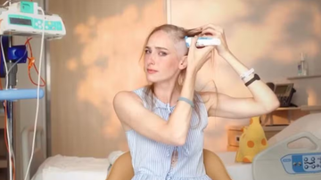 Atriz Dani Gondim trajando azul e raspando os cabelos sob fundo de quarto de hospital