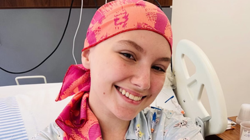 Jovem Isabel Veloso posando sorridente com turbante na cabeça.