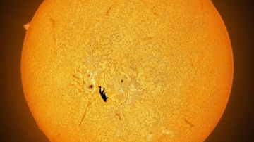 Imagem de disco solar com silhueta de paraquedista em queda livre.