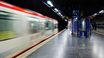 plataforma de estação de metrô com trem em movimento ao fundo.