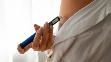 mulher aplicando caneta emagrecedora em seu abdômen.