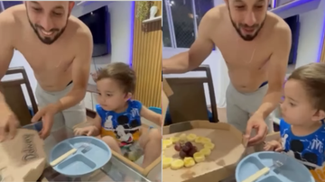 Pai e filho em casa, com pai tentando dar frutas para o filho.