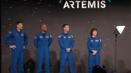 Astronautas reunidos em palco em frente a letreiro com o nome da missão.