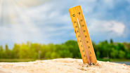 Termometro marcando altas temperaturas com praia ao fundo.
