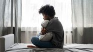 Pessoa sentada na cama apresentando sintomas de depressão.