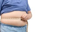 Indivíduo acima do peso medindo barriga.