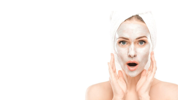 Mulher fazendo skincare com máscara facial branca.