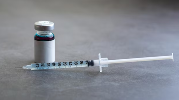 Medicamento injetável disposto sobre mesa.