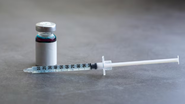 Medicamento injetável disposto sobre mesa.