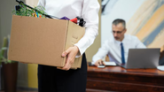 Homem se despedindo de seu antigo trabalho carregando caixa com seus pertences.