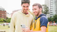 Homens olhando ao celular e sorrindo.