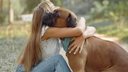 mulher e cachorro se abraçando de forma terna.