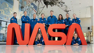 Astronautas da Nasa ao lado de letreiro com logo da agência.