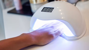indivíduo com mão dentro de cabine de luz UV.