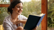 Mulher lendo livro novo em casa.