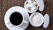 xícara de café ao lado de açucareiro.